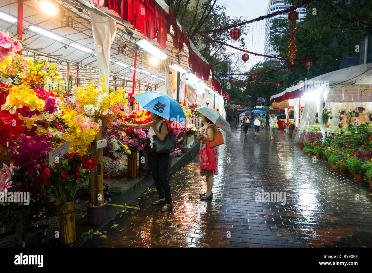 Singaporean ladies at flower market, with umbrellas in the rain