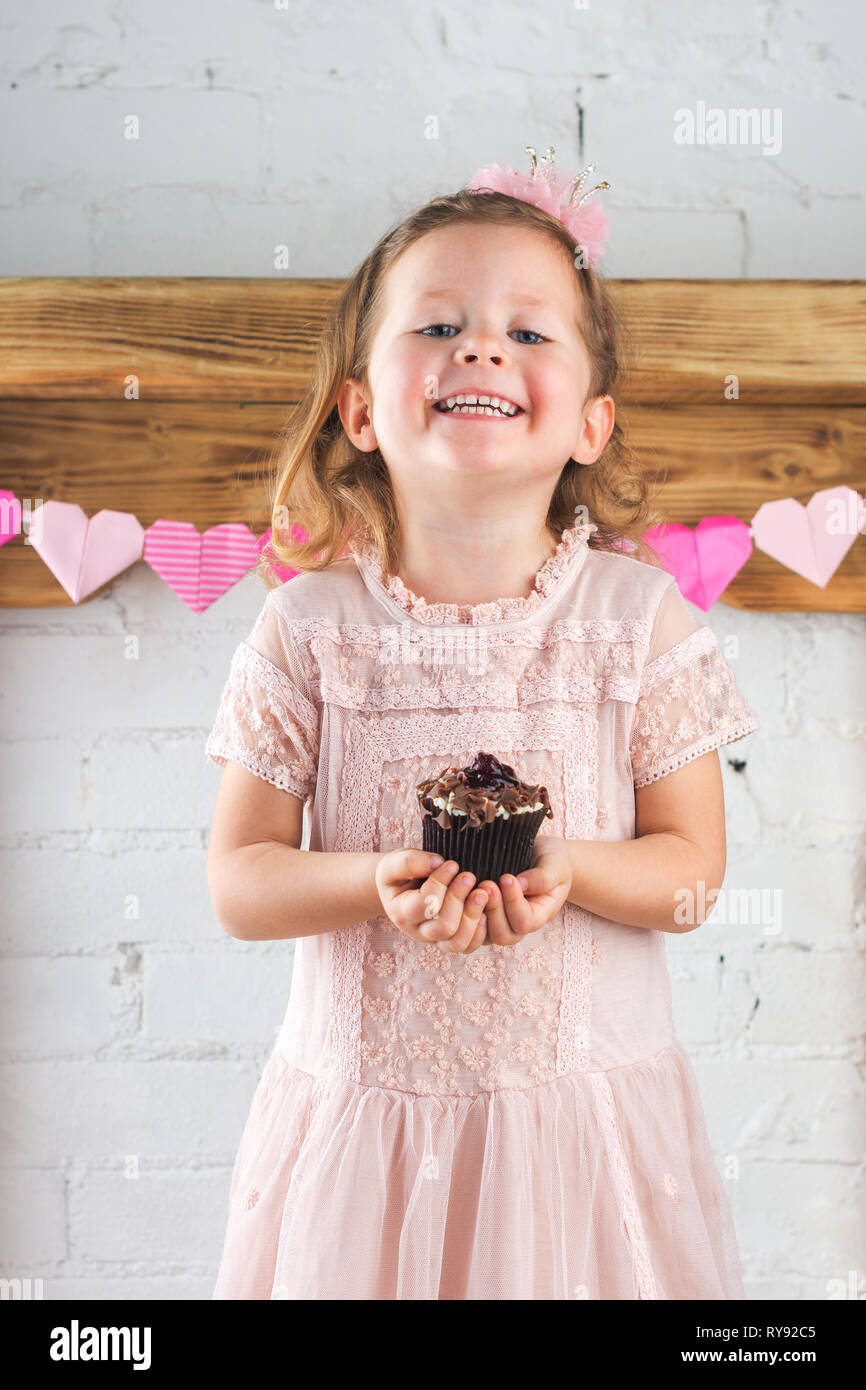 Little Girl In Pastel Pink Dress And Crown Headband Holding