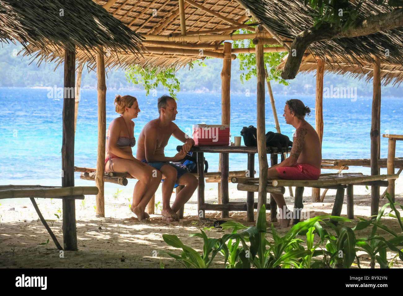 European tour group under bamboo beach hut - Linapacan Island, Palawan - Philippines Stock Photo