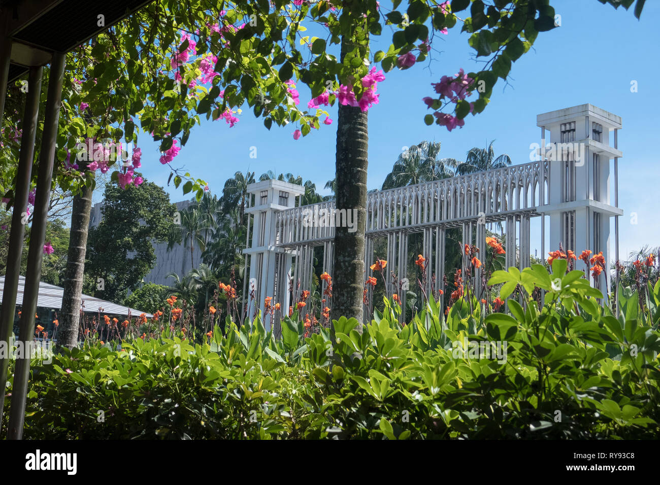 Monument in Estana Park, With colorful pink and orange flowers on covered walkway - Singapore Stock Photo