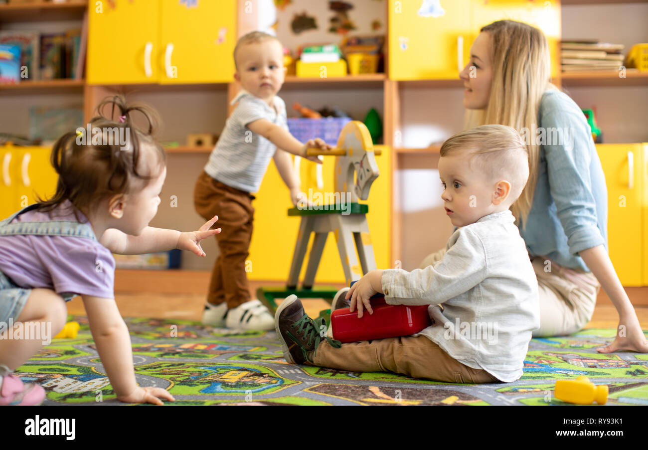 Nursery babies with mentor playing in kindergarten Stock Photo - Alamy