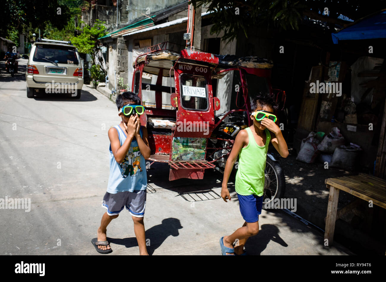 Young Filipino boys plying in the street with diving goggles on - Romblon Island, Philippines Stock Photo