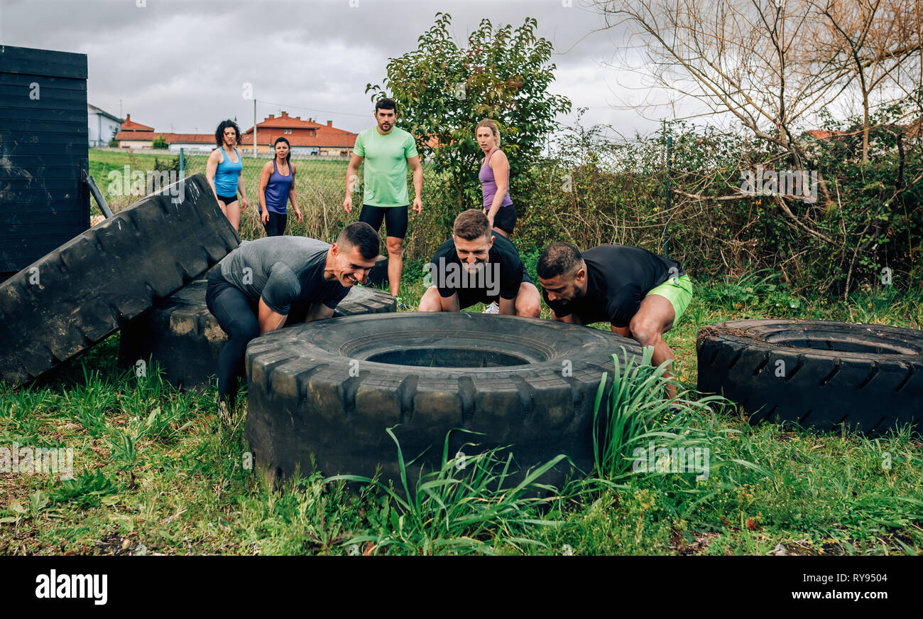 Participants in an obstacle course turning a wheel Stock Photo
