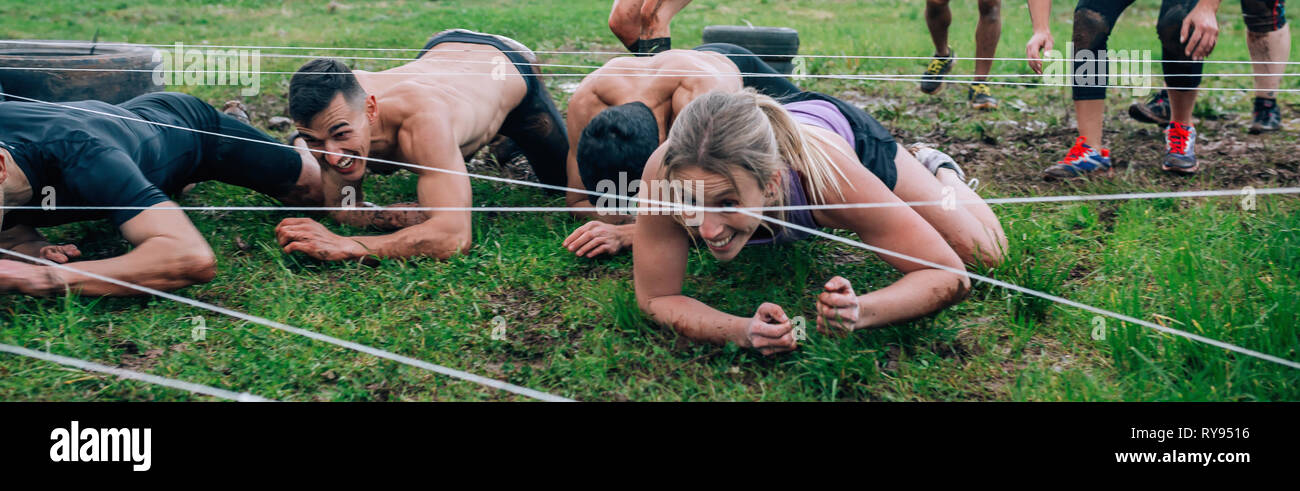 Participants in an obstacle course crawling Stock Photo