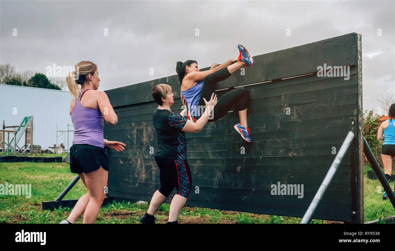 Female participants in obstacle course climbing wall Stock Photo
