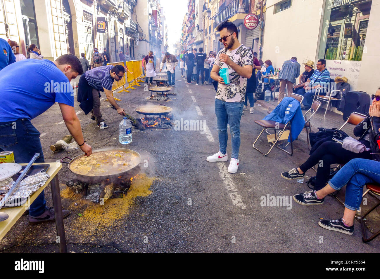 Members of Fallas preparing paella on the street and then having lunch together, Fallas party Funfair Valencia, Barrio El Botanico Stock Photo