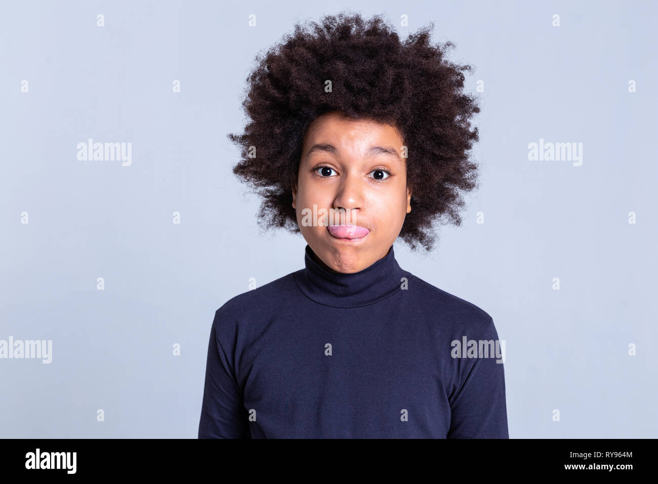 Childish young boy with afro hairstyle exposing his tongue Stock Photo