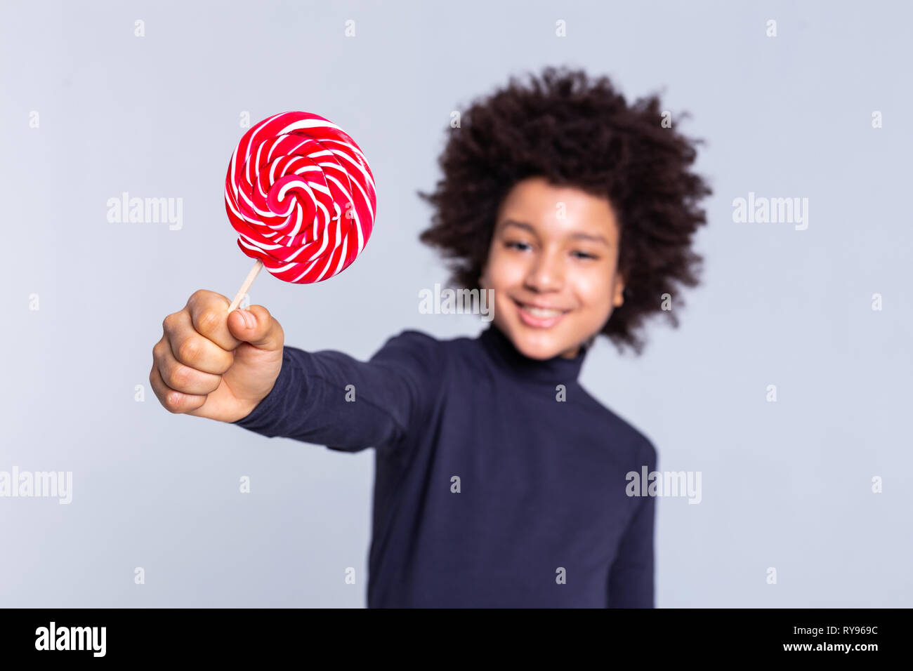 Resolute dark-haired joyful boy pulling out hand with candy in it Stock Photo