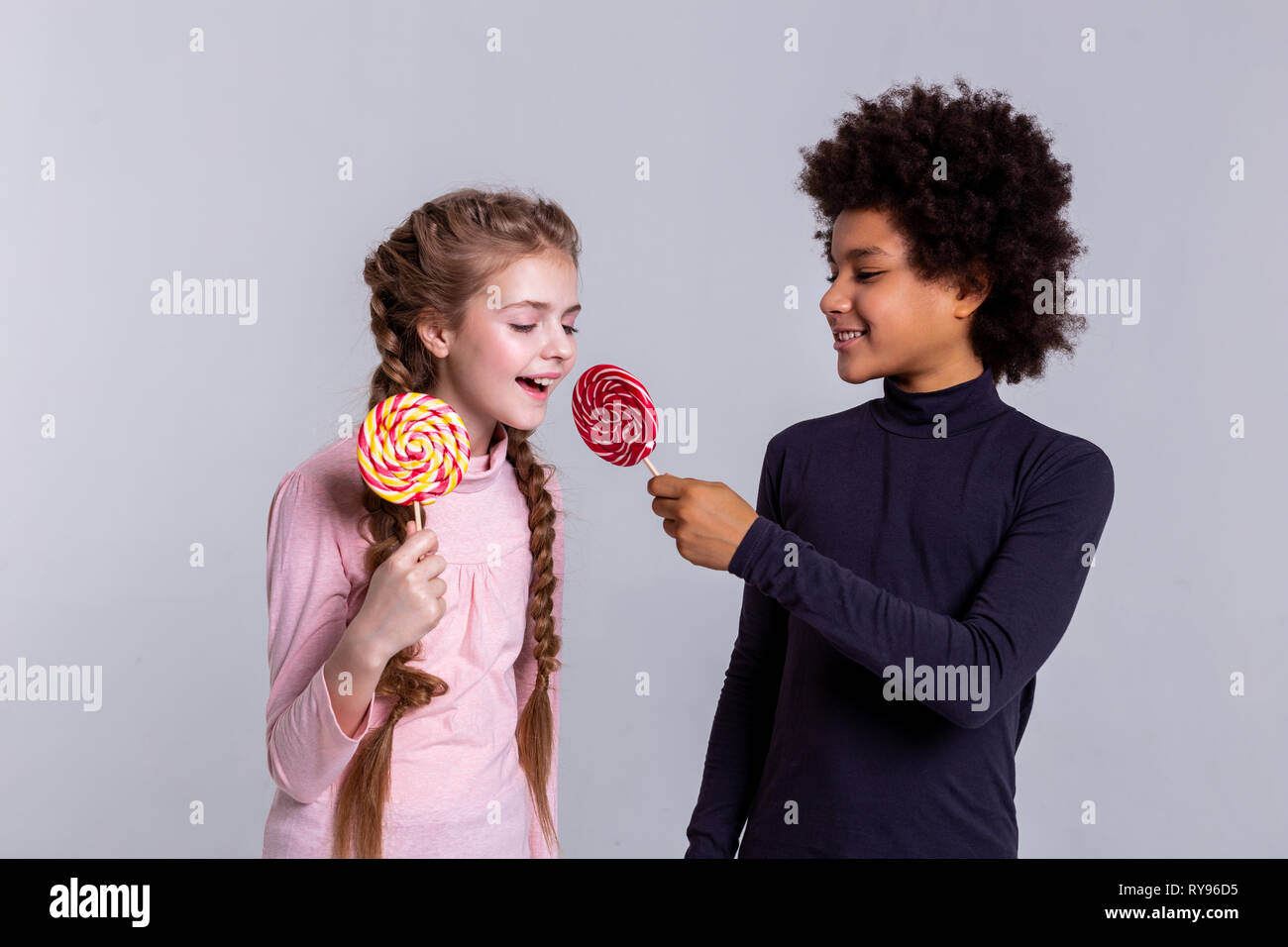 Smiling African American dark-haired boy proposing his red candy Stock Photo