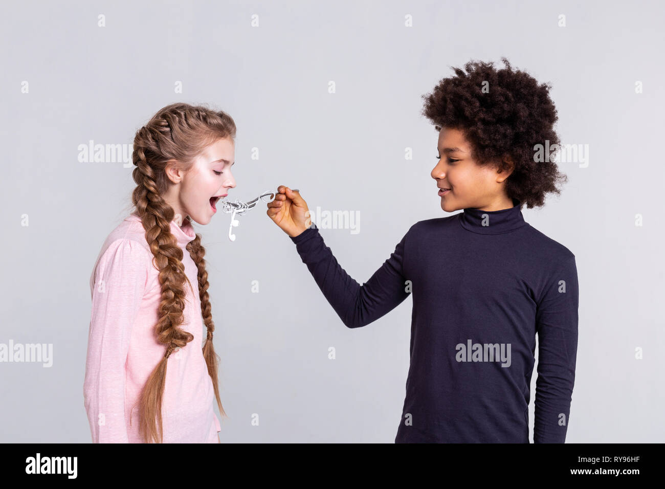Resolute boy with wild hair feeding his girlfriend with headphones Stock Photo
