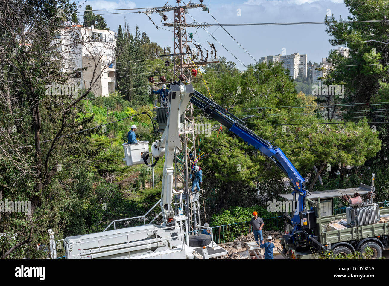 Haifa, Israel- February 26, 2019 :Electric company team working on a transmission tower using two truck lifts Stock Photo