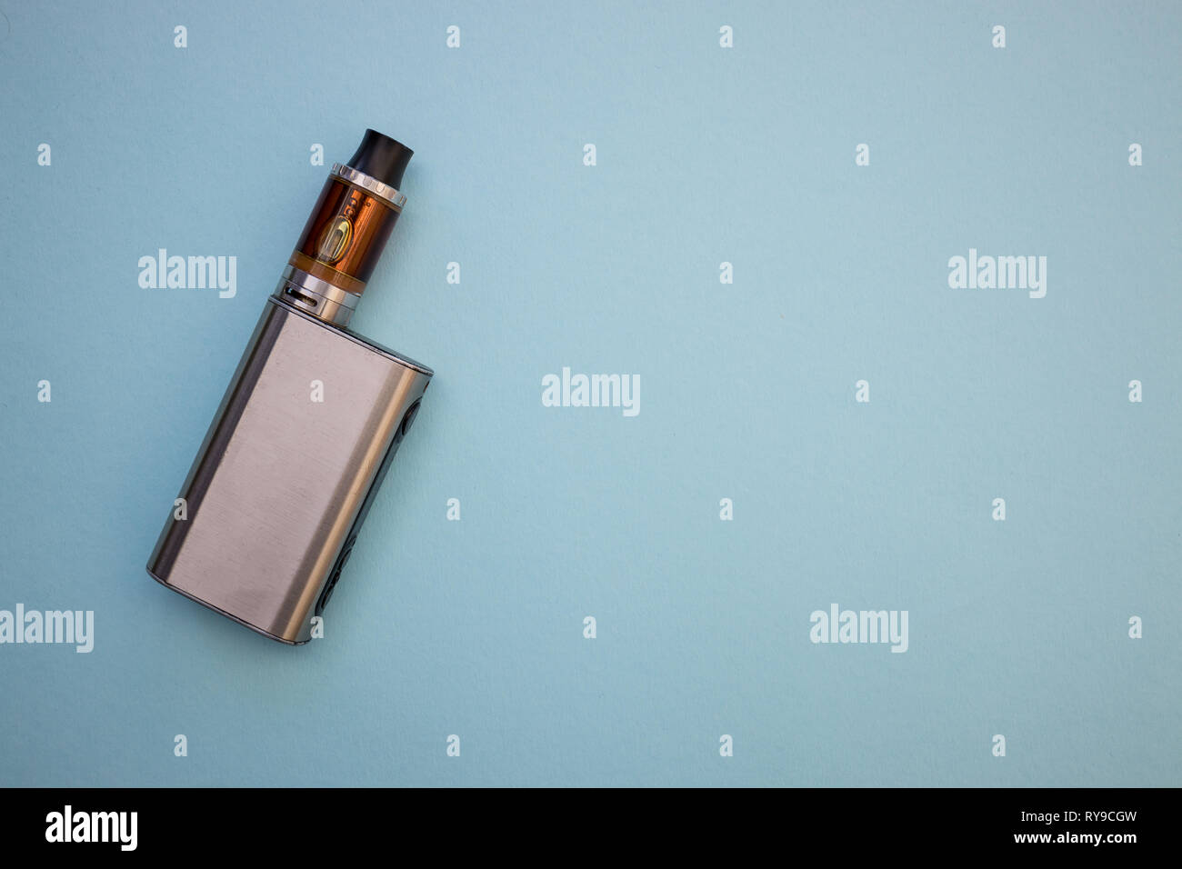 Vape pen metal electronic cigarette with vaping blue background top view Stock Photo