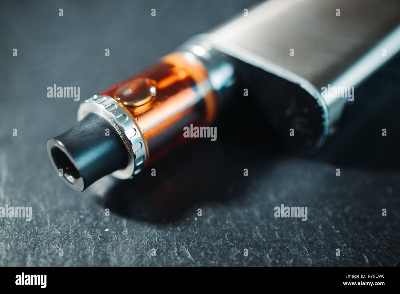 Vape pen metal electronic cigarette with vaping dark background Stock Photo
