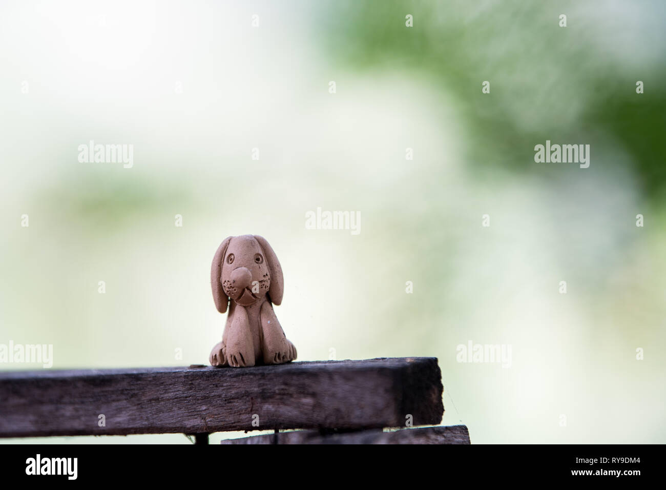 Clay doll dog, molded from clay and through heat, on wood. Stock Photo