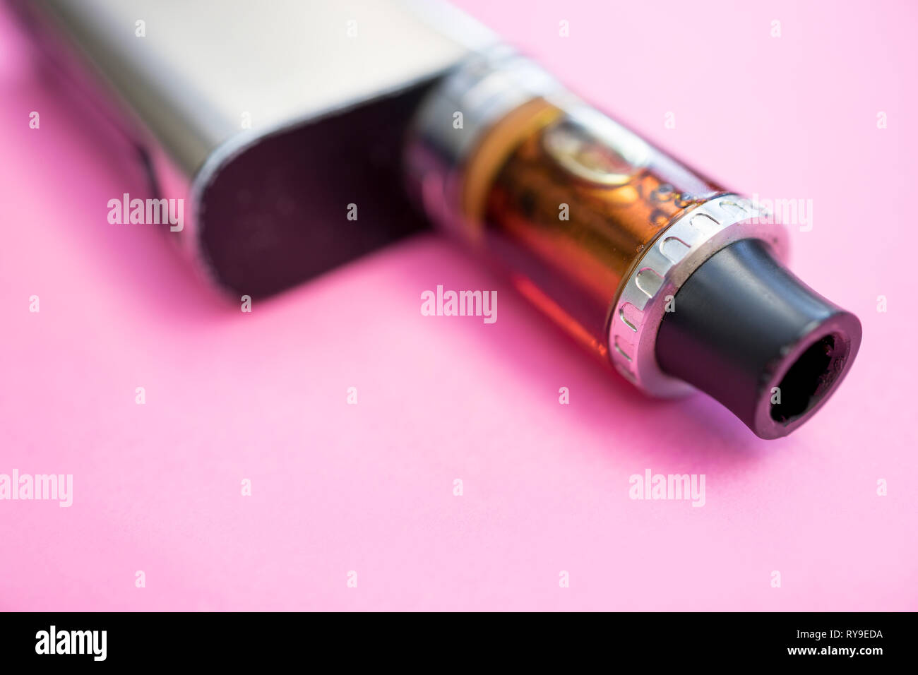 Vape pen metal electronic cigarette vaping pink background Stock Photo