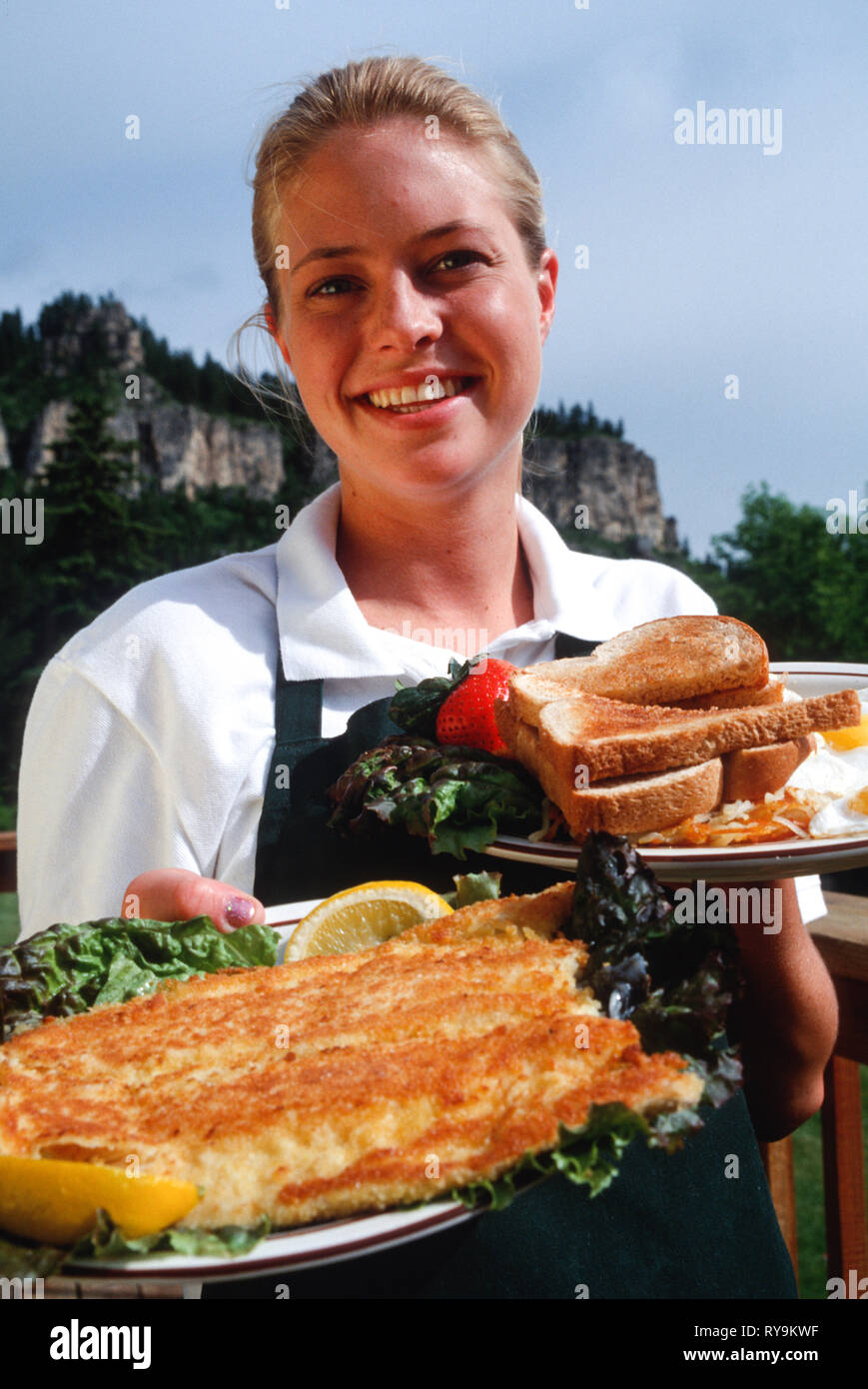 Young Waitress Delivers a Fried Fish and Eggs Breakfast Platter