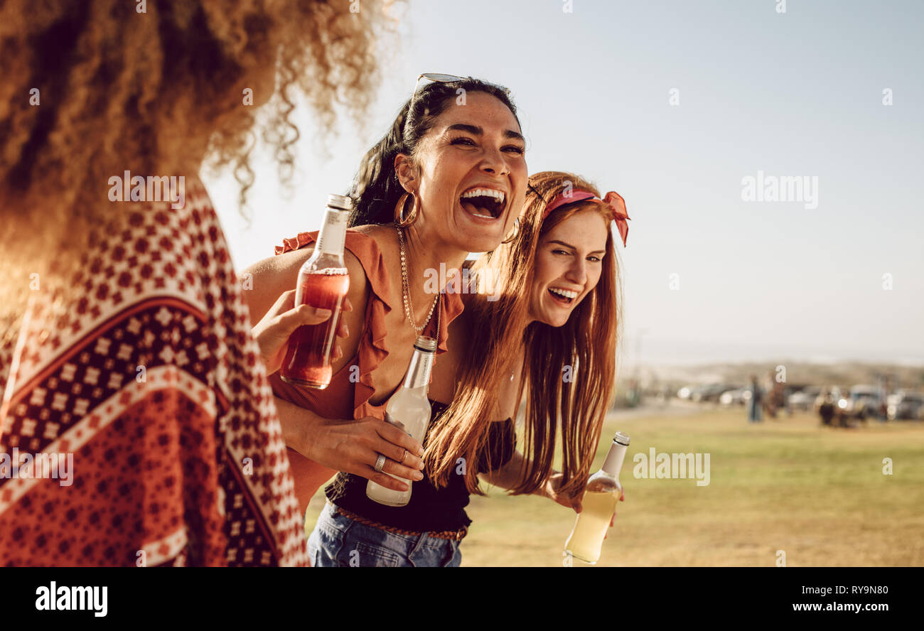 Three young women walking outdoors together and laughing. Group of multi-ethnic female friends having fun outdoors. Stock Photo