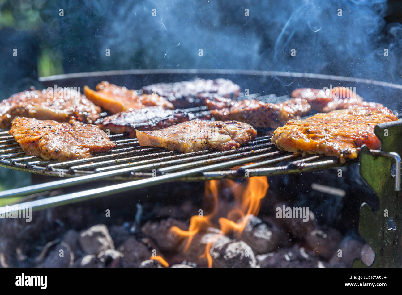 Bauchfleisch und Wuerstchen auf dem Grill, unter dem Grill lodern die Flammen bei THEMENBILD Grillen, 06.05.2018 Foto: Mario Hommes Stock Photo