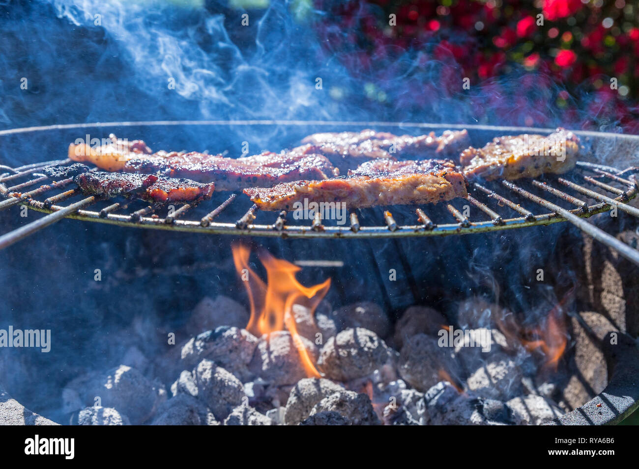 Bauchfleisch und Wuerstchen auf dem Grill, unter dem Grill lodern die Flammen bei THEMENBILD Grillen, 06.05.2018 Foto: Mario Hommes Stock Photo