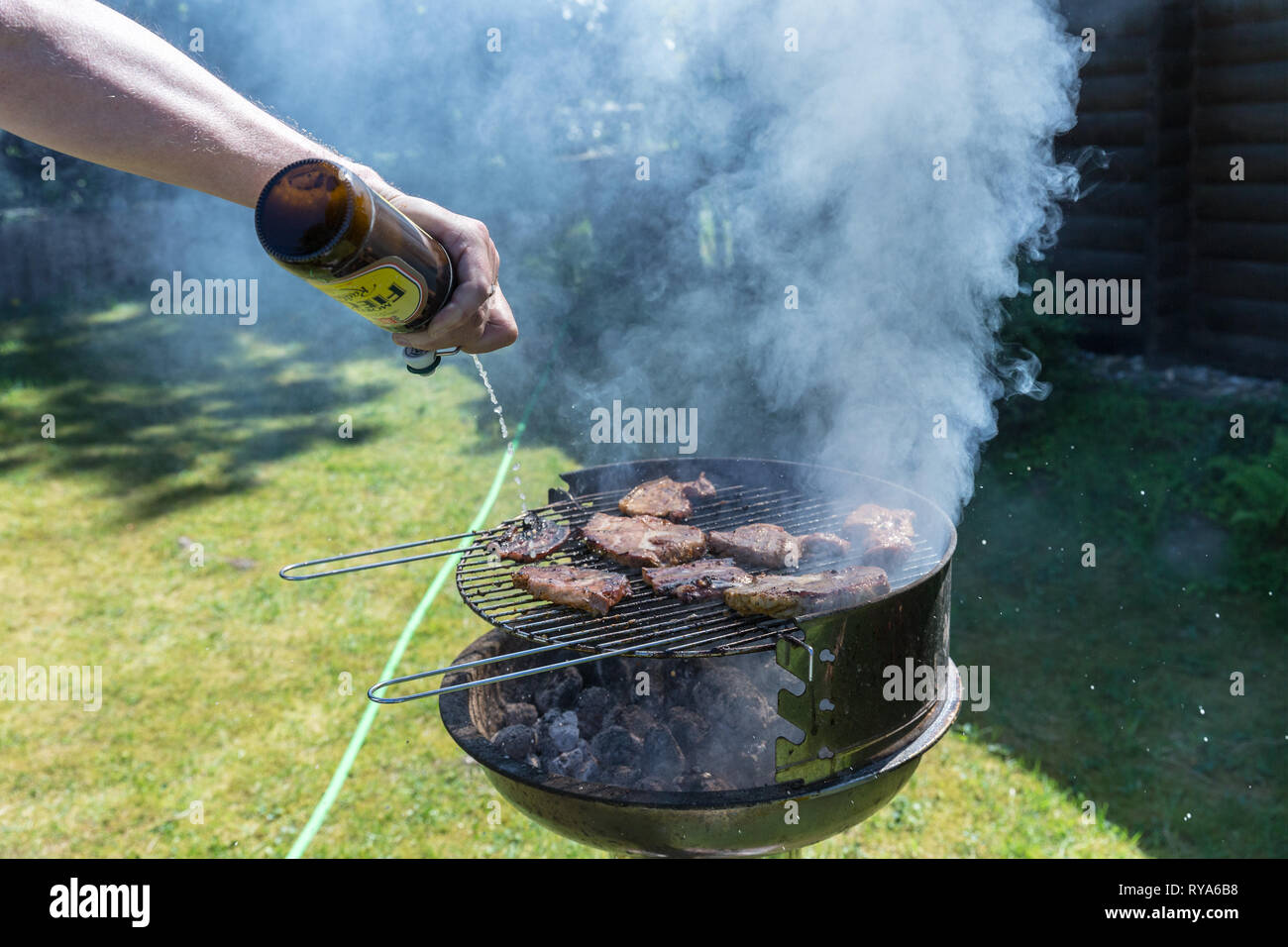 Bauchfleisch und Wuerstchen auf dem Grill, das Fleisch wird mit Bier abgeloescht bei THEMENBILD Grillen, 06.05.2018 Foto: Mario Hommes Stock Photo