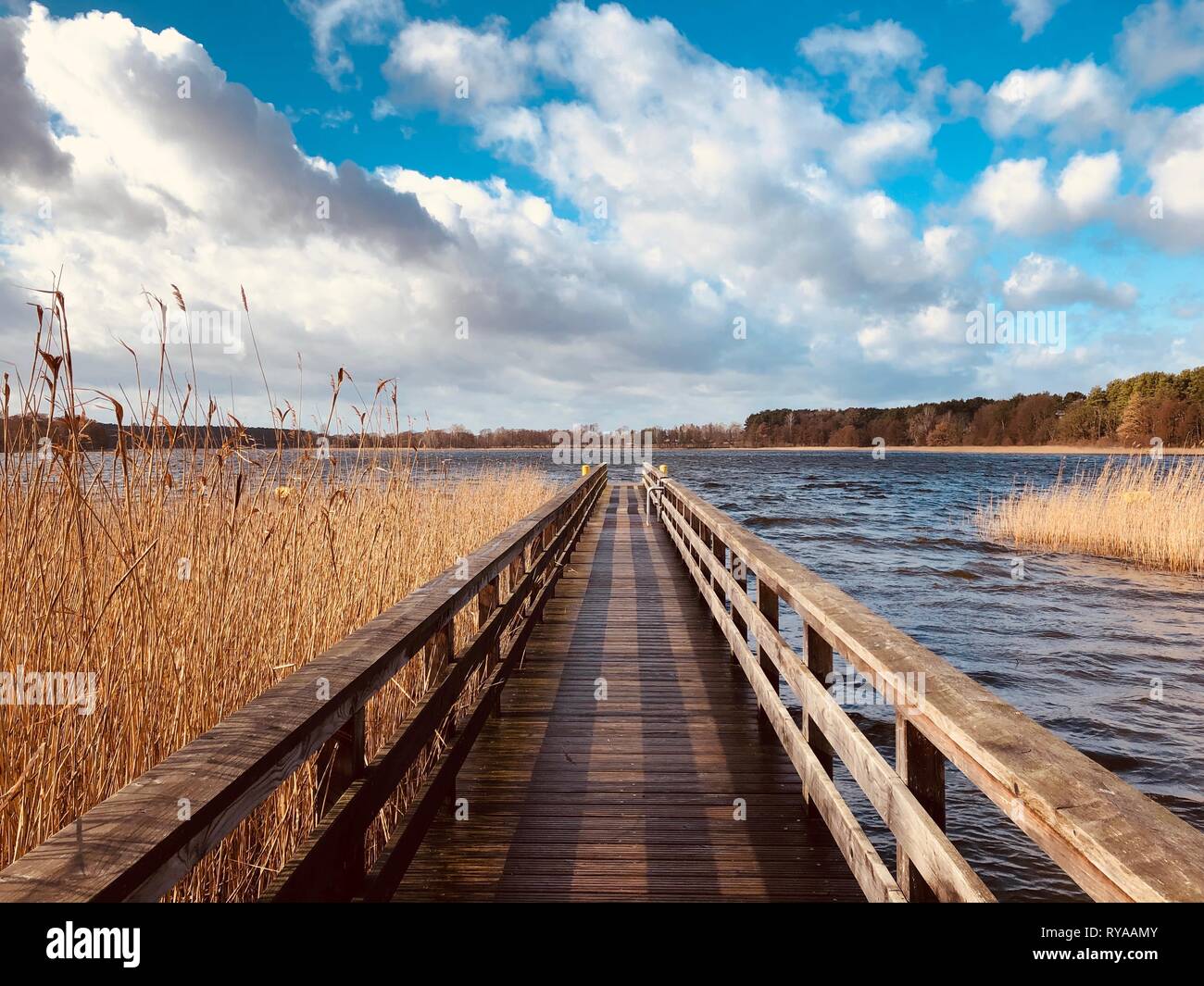 wooden pier at waterside - straight wood dock walkway at lake - Stock Photo