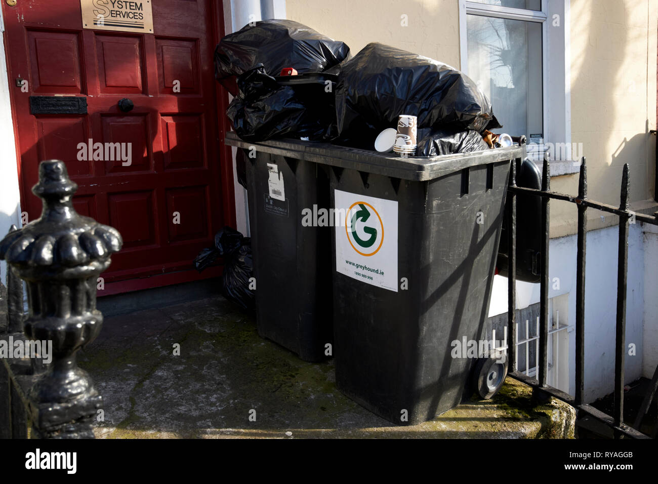 overflowing private company wheelie bins outside a georgian house made into offices Dublin Republic of Ireland Europe Stock Photo