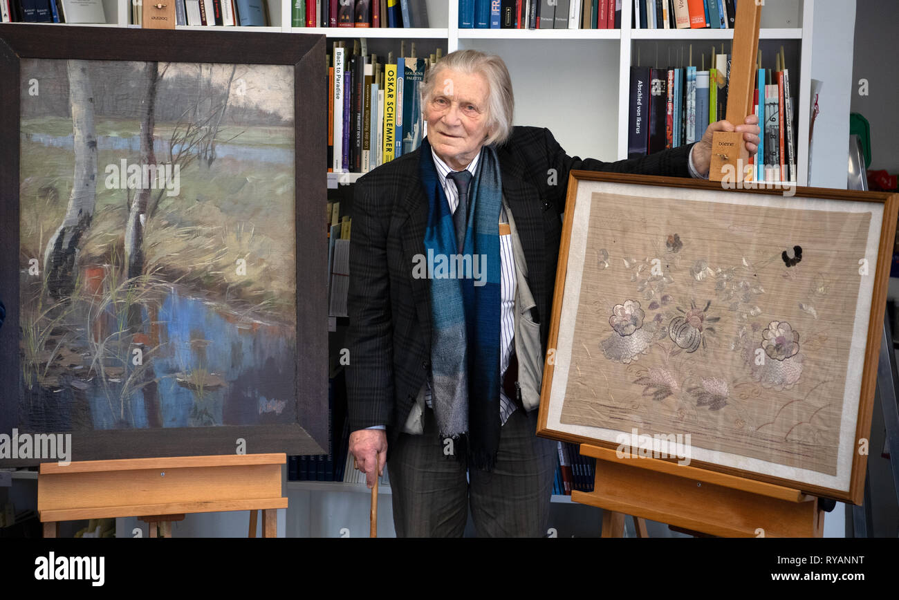 Potsdam, Germany. 13th Mar, 2019. Klaus Runze, grand-nephew of the painter Hannah Schreiber de Grahl (1864-1930), stands between two of the artist's works in the Potsdam Museum during a press conference on the transfer of works of art. Credit: Ralf Hirschberger/dpa/ZB/dpa/Alamy Live News Stock Photo