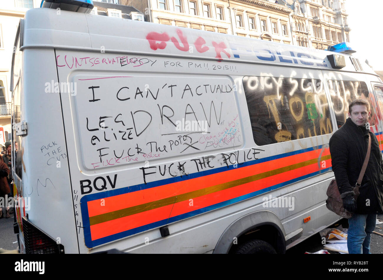 Student demos against govt cuts and top up fees . Trafalgar Square and Whitehall. A parked empty police van became the focus of many of the protestors' frustrations with small groups of hooded youths vandalising the vehicle: clambering onto the roof, writing  graffiti on the body work and smashing its windows and sirens . The presence of the van however alerted suspicions with many demonstrators alleging that the vehicle had been placed deliberately as a target which could then be retrospectively cited as  justification for heavier handed police intervention or to simply further isolate the st Stock Photo