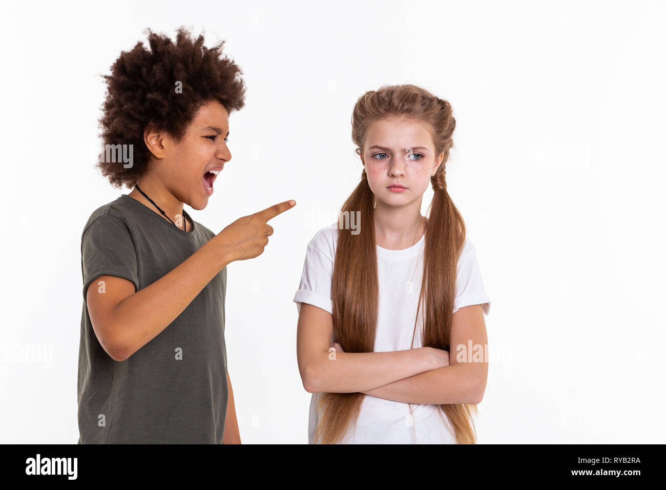 Angry long-haired girl resolutely crossing hands while boy pointing at her Stock Photo
