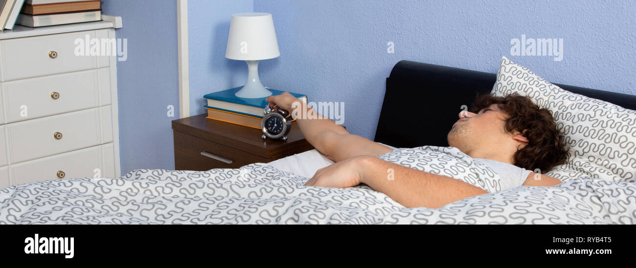 Young man stopping the alarm clock Stock Photo
