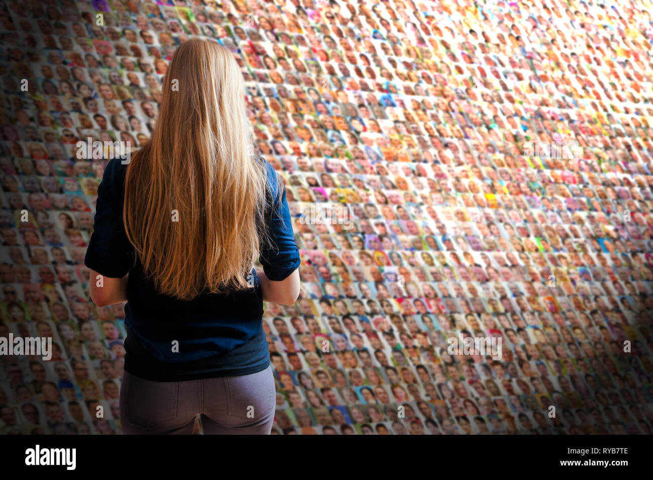 blonde woman with long hair standing in front of a wall with many ...