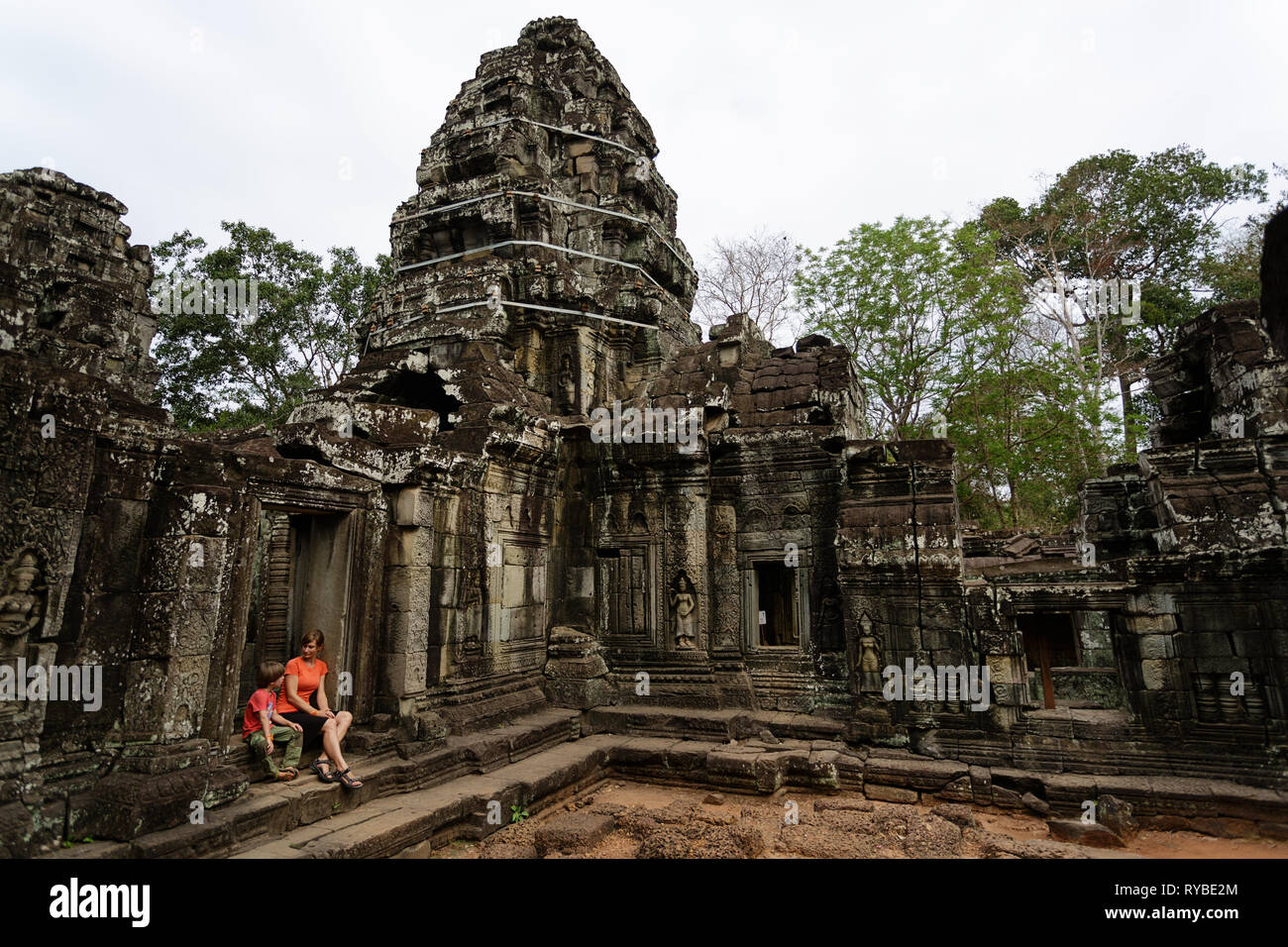 Mother and son at Ta Promh temple at Angkor, Cambodia overgrown with tree roots Stock Photo