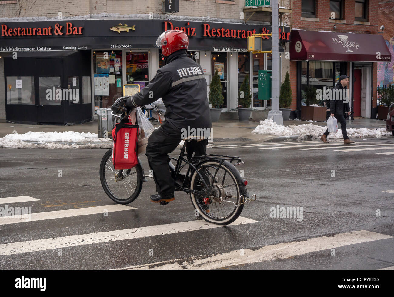A deliveryman from GrubHub on his electric bike crosses Fulton Street making deliveries in the Fort Greene neighborhood of New York on Saturday, March 2, 2019. (Â© Richard B. Levine) Stock Photo