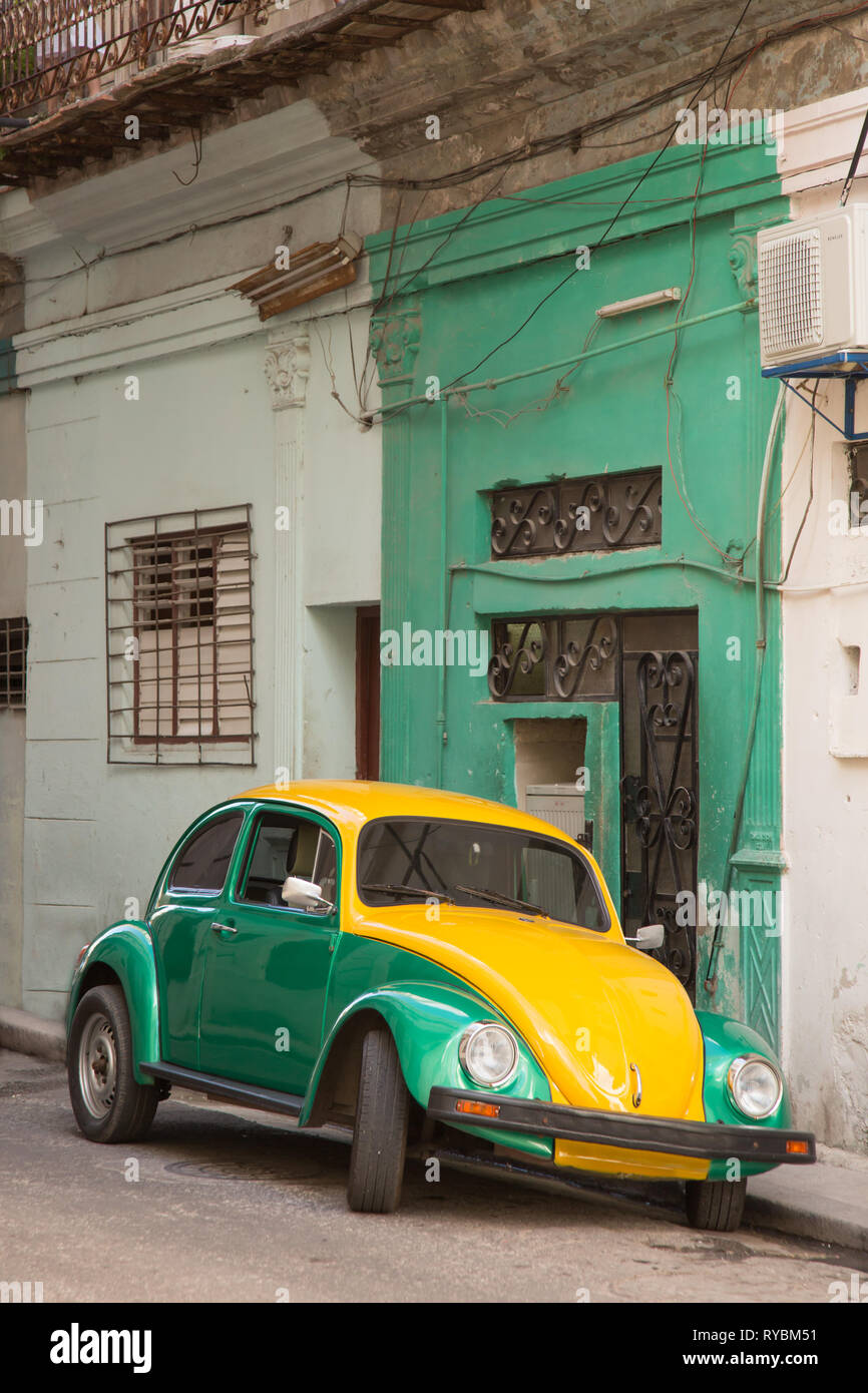 Old Volkswagen Beetle parked in Old Havana Street in front of matching house. Stock Photo