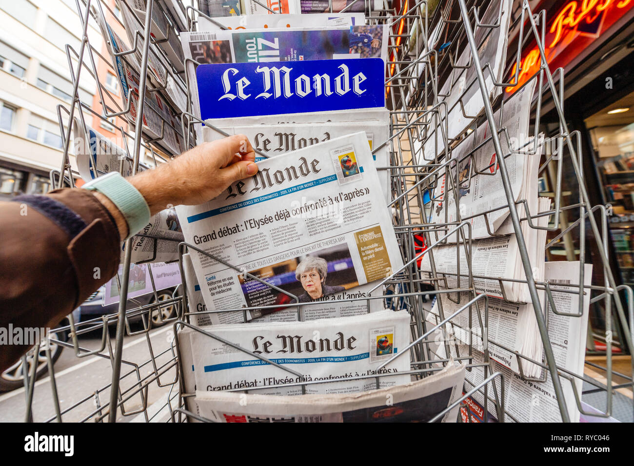 Paris, France - Mar 12, 2019: Man buying from kisok stand French newspaper Le Monde featuring on the cover Theresa May and last deals about Brexit Stock Photo
