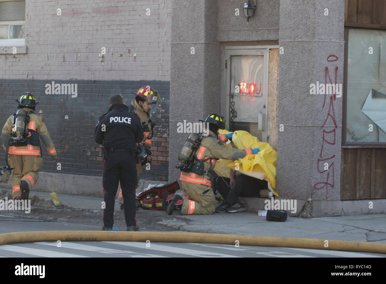 Hamilton, Canada 2019: Firefighters and police attend to a victim of smoke inhalation after an apartment building fire. Rescuing people from a fire. Stock Photo