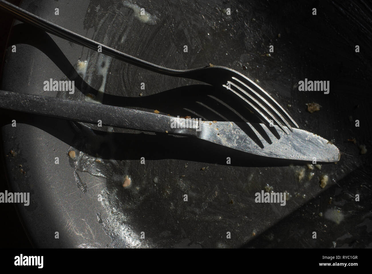 a dirty black plate after a meal with silverware Stock Photo