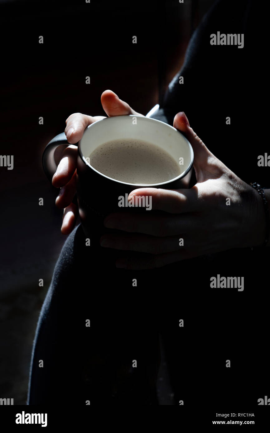 middle aged woman sits with a cup of coffee Stock Photo
