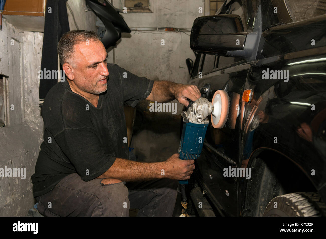Man working with a grinding machine on car paint Stock Photo