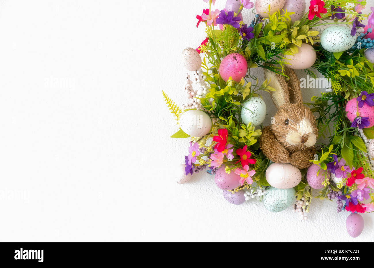 a colorful easter bunny wreath with colored eggs and flowers and white ...