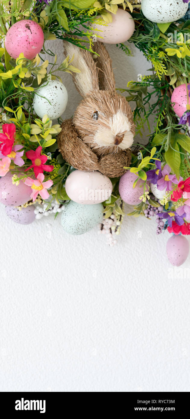 a colorful easter bunny wreath with colored eggs and flowers and white ...