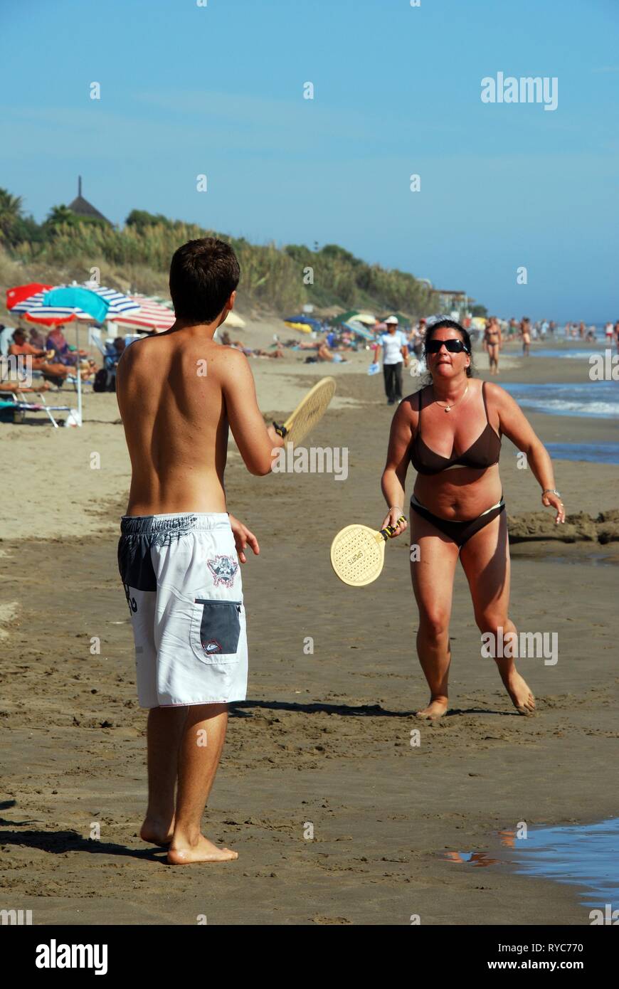 Couple playing bat and ball on Playa de la Vibora beach, Elviria, Marbella, Costa del Sol, Andalusia, Spain, Europe. Stock Photo