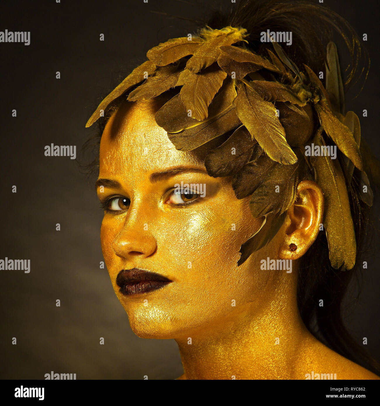 Young girl with face painted gold Stock Photo