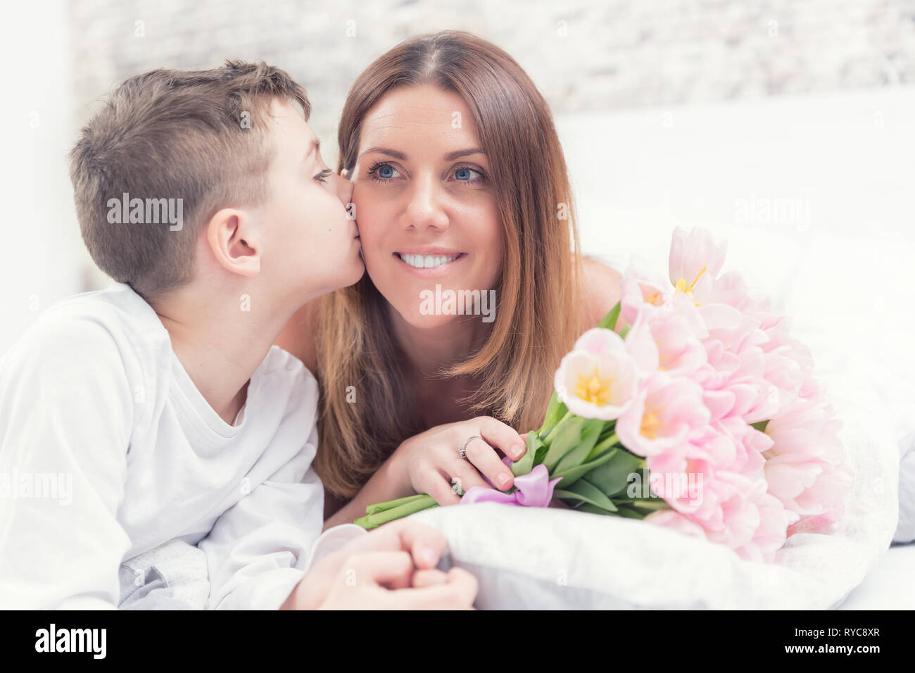 Happy Mother S Day Concept Mom With Son On Bed With T And Tulips Son Kisses His Mom Stock