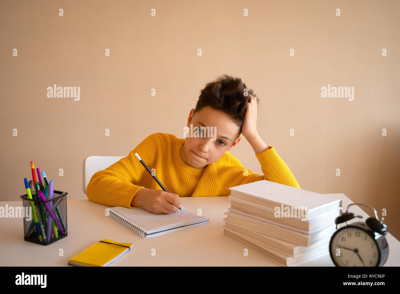 Thinking child bored, frustrated and fed up doing his homework Stock Photo