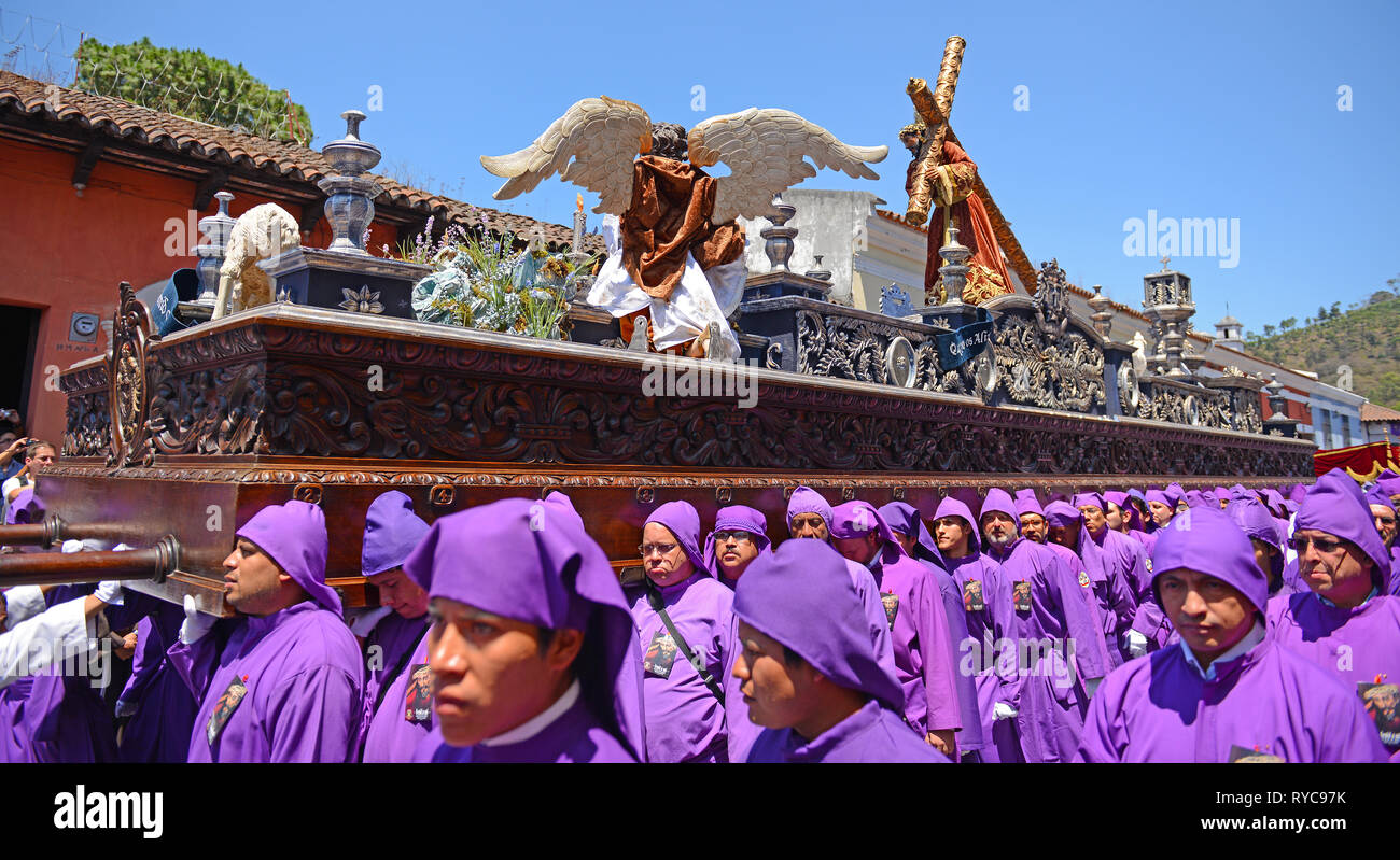 The procession of the cucuruchos in Antigua city during Easter with the people in purple being penitents for the sins comitted, Guatemala. Stock Photo