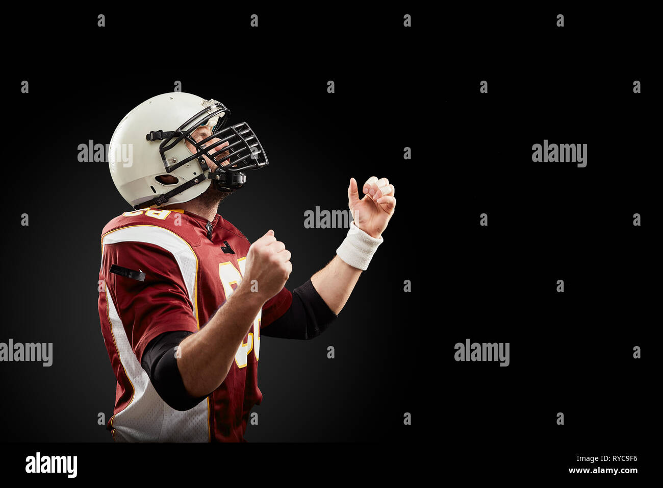 Isolated American football player rejoices in victory in black background Stock Photo