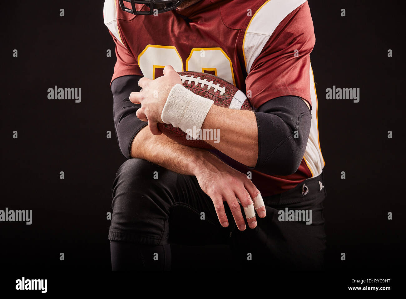 American football player sitting in a position of readiness, hands to keep  a mache on a black background, concept Stock Photo - Alamy