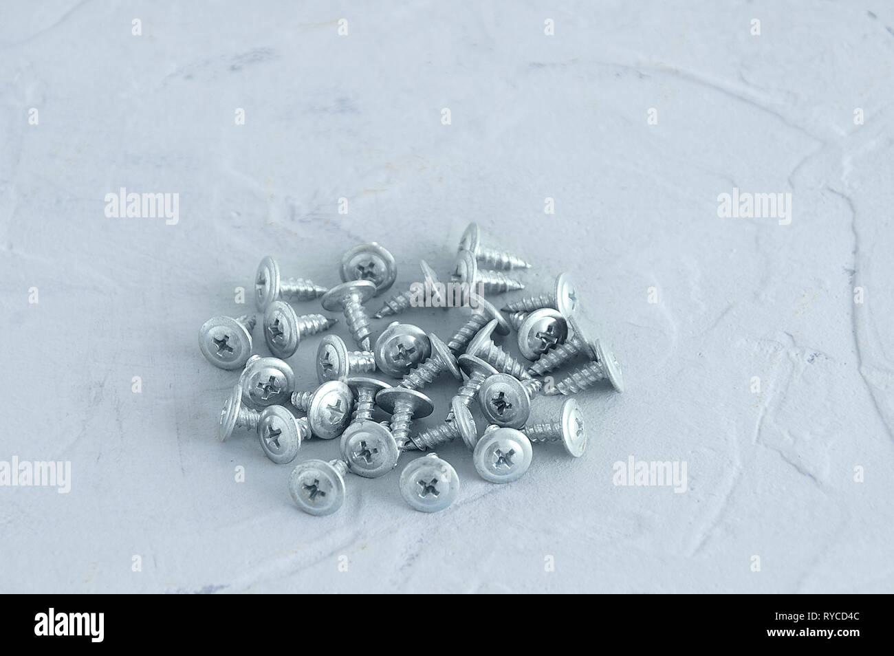 Silvery metal screws for plasterboard walls. On a gray concrete background. Close-up. Side view Stock Photo