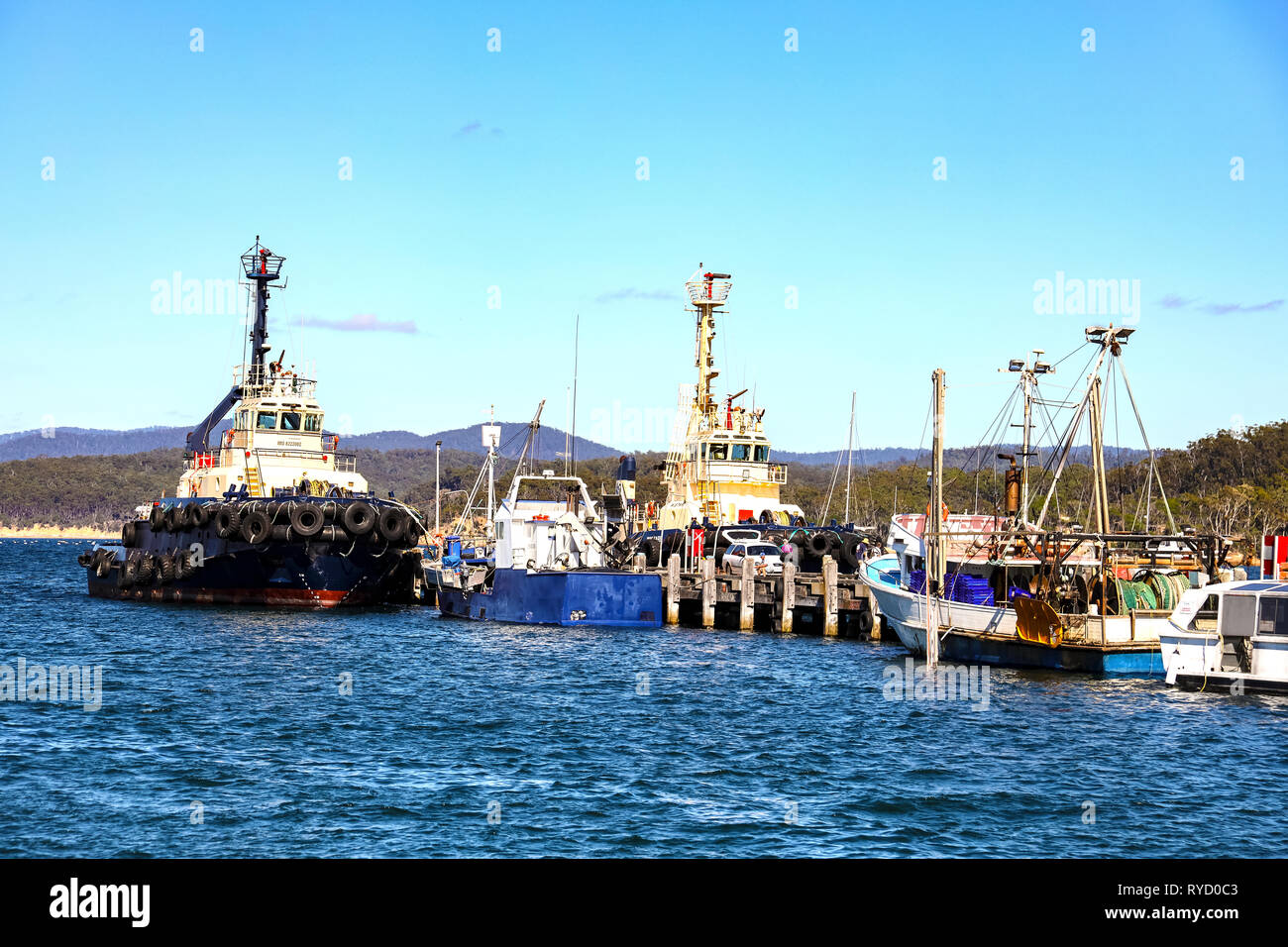 Tug boat and fishing trawlers tied up at wharf in Eden Harbour on Two Fold Bay on the New South Wales southern cost Stock Photo